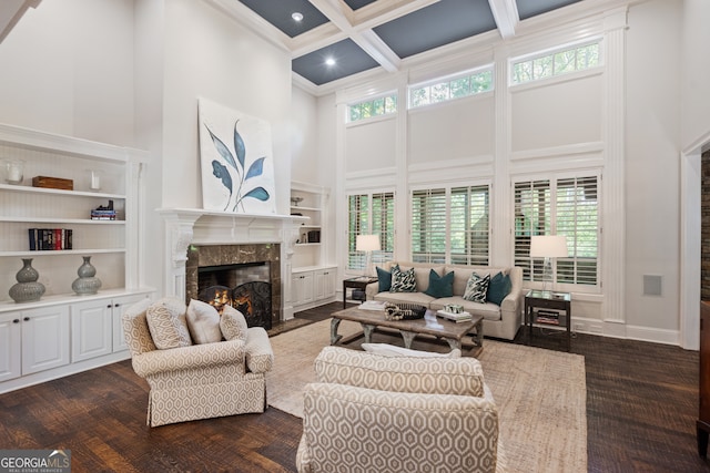 living room with a towering ceiling, coffered ceiling, beamed ceiling, a premium fireplace, and dark hardwood / wood-style floors