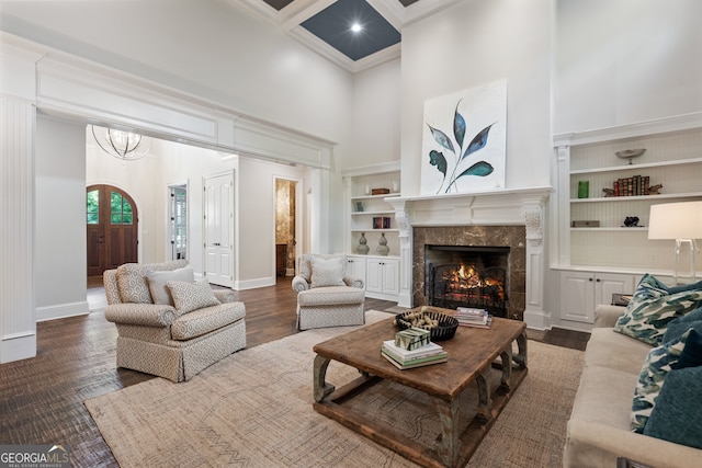 living room featuring a fireplace, a towering ceiling, ornamental molding, and dark hardwood / wood-style floors