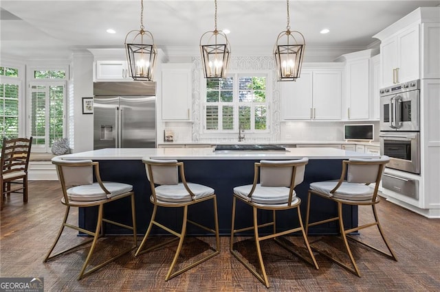 kitchen featuring a large island, white cabinetry, stainless steel appliances, and decorative light fixtures