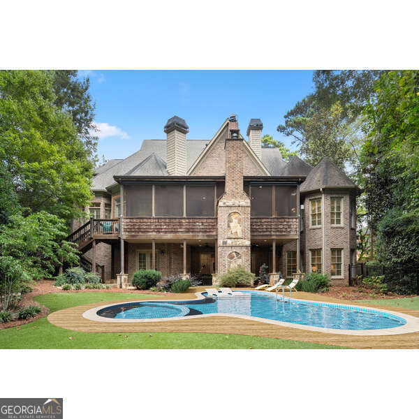 rear view of property featuring a patio, a pool side deck, a lawn, and a sunroom