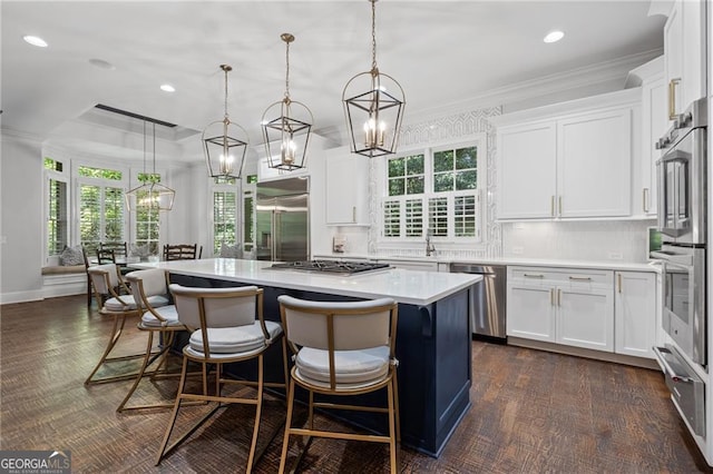 kitchen with appliances with stainless steel finishes, a center island, pendant lighting, and white cabinets