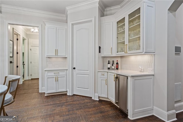 bar with white cabinetry, backsplash, and stainless steel refrigerator