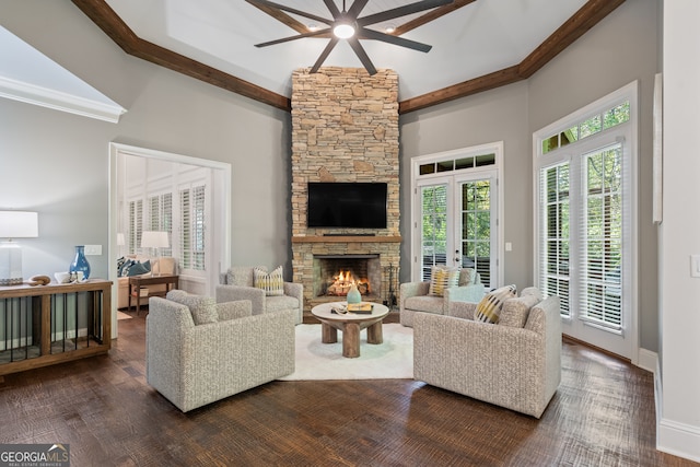 living room featuring ornamental molding, a stone fireplace, dark hardwood / wood-style floors, and ceiling fan