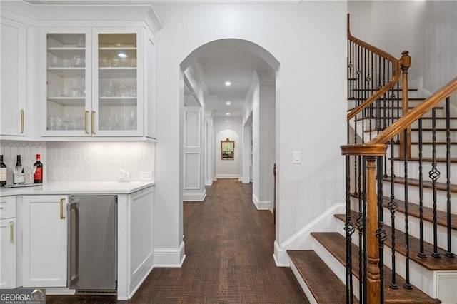 interior space featuring backsplash, dark hardwood / wood-style flooring, stainless steel fridge, white cabinets, and crown molding