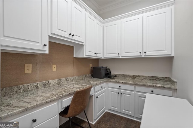 kitchen featuring built in desk, crown molding, and white cabinetry