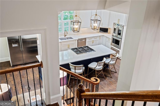 kitchen with appliances with stainless steel finishes, sink, white cabinetry, and an inviting chandelier