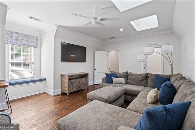 living room featuring crown molding, vaulted ceiling with skylight, dark hardwood / wood-style floors, and ceiling fan