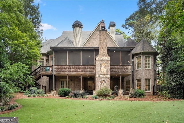 rear view of property featuring a sunroom, a deck, and a lawn