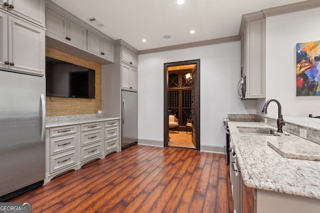 kitchen with light stone countertops, appliances with stainless steel finishes, sink, ornamental molding, and dark hardwood / wood-style floors