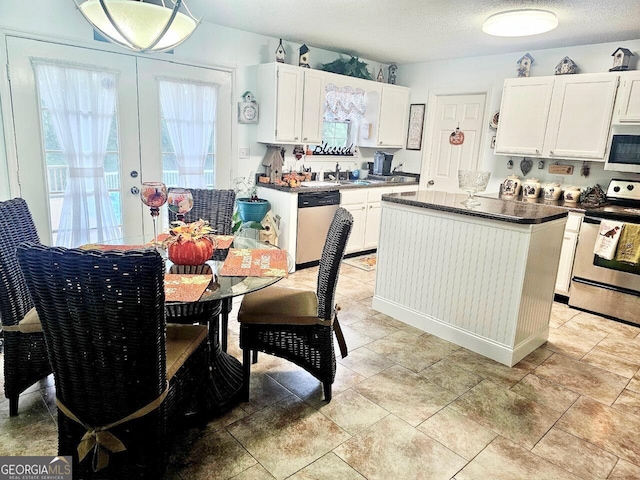 kitchen with white cabinets, appliances with stainless steel finishes, a center island, and sink