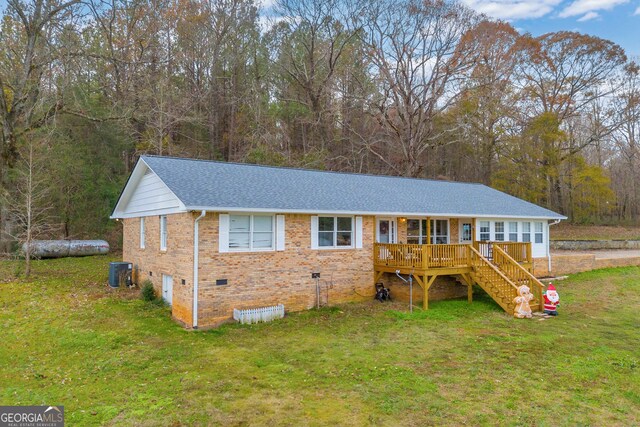 view of front facade featuring central air condition unit, a wooden deck, and a front lawn