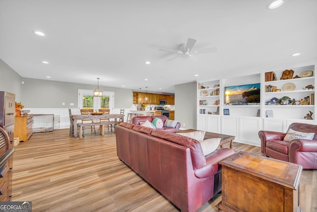 living room with light hardwood / wood-style floors, built in features, and ceiling fan