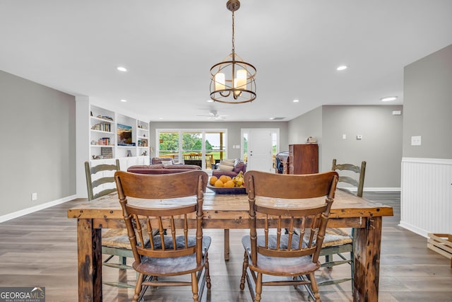 dining space with wood-type flooring and ceiling fan with notable chandelier