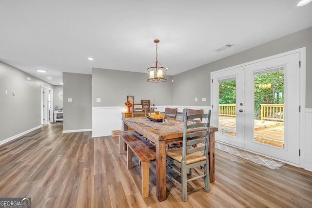 dining area featuring a notable chandelier, light wood-type flooring, and french doors