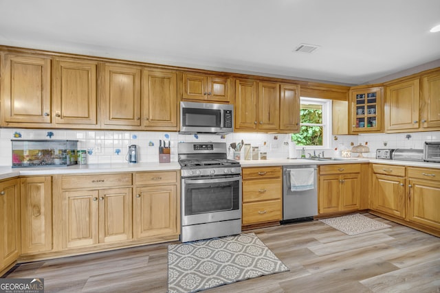 kitchen featuring backsplash, stainless steel appliances, light hardwood / wood-style flooring, and sink