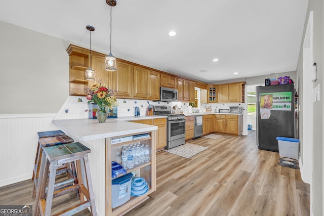 kitchen with decorative light fixtures, light hardwood / wood-style floors, kitchen peninsula, and appliances with stainless steel finishes