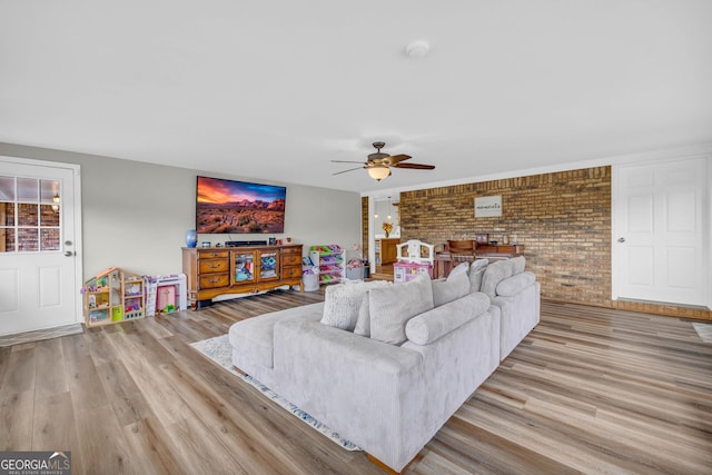 living room featuring ceiling fan, brick wall, and light hardwood / wood-style flooring