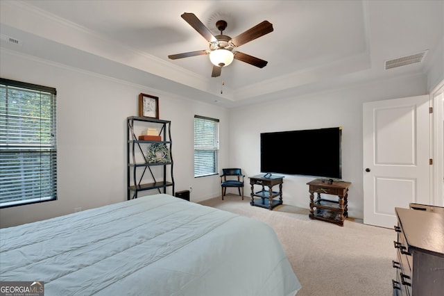 bedroom featuring a raised ceiling, crown molding, ceiling fan, and light carpet