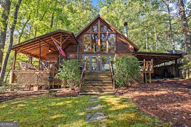 rear view of property featuring a wooden deck and a lawn