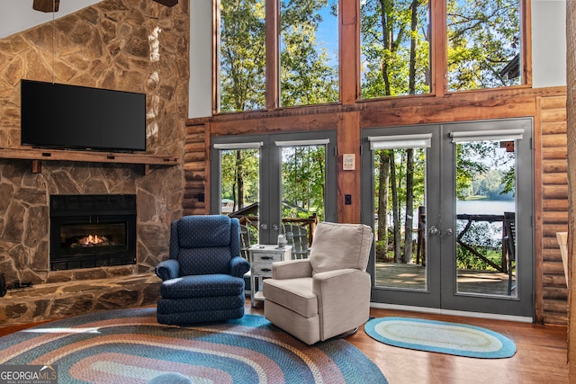 interior space featuring hardwood / wood-style flooring, a stone fireplace, a towering ceiling, and a wealth of natural light