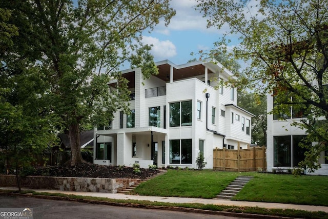 contemporary home featuring a balcony and a front yard