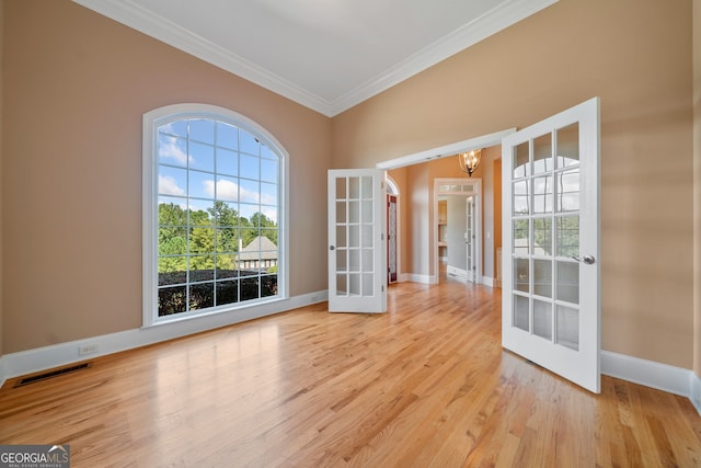 spare room with crown molding, light hardwood / wood-style floors, french doors, and a notable chandelier