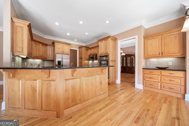 kitchen with appliances with stainless steel finishes, kitchen peninsula, a kitchen breakfast bar, and light hardwood / wood-style flooring