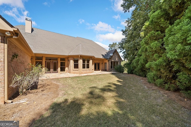 rear view of house with a lawn and a patio