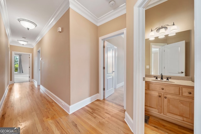 hallway with light hardwood / wood-style flooring, crown molding, and sink