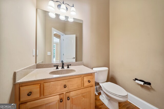 bathroom with hardwood / wood-style floors, vanity, and toilet