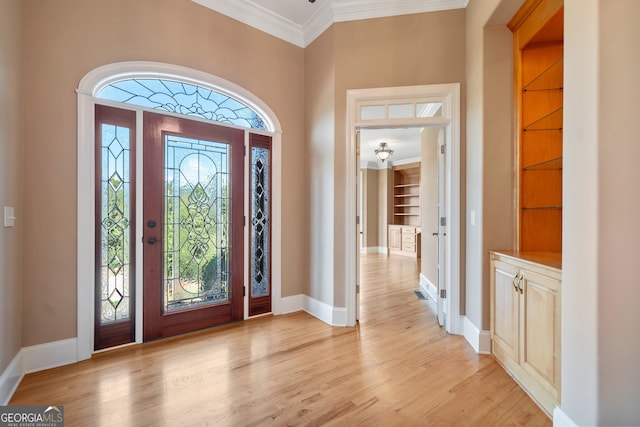 entrance foyer with ornamental molding and light hardwood / wood-style flooring