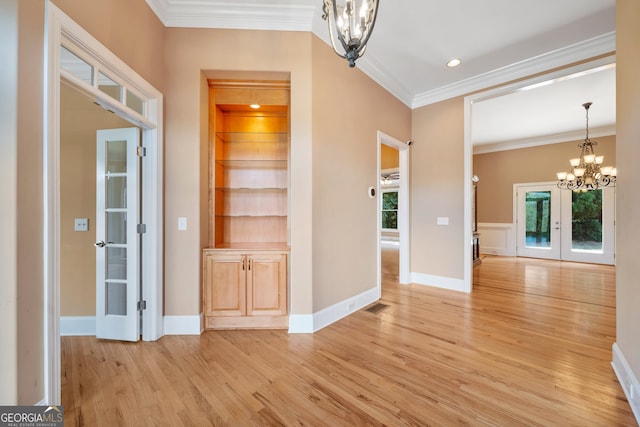 unfurnished dining area featuring french doors, light hardwood / wood-style flooring, a chandelier, and ornamental molding