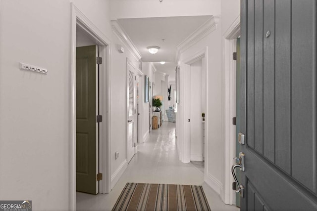 hallway with crown molding and light tile patterned floors