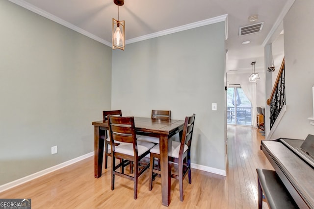 dining area with ornamental molding and light hardwood / wood-style flooring