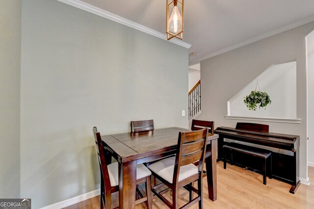 dining room featuring light wood-type flooring and crown molding