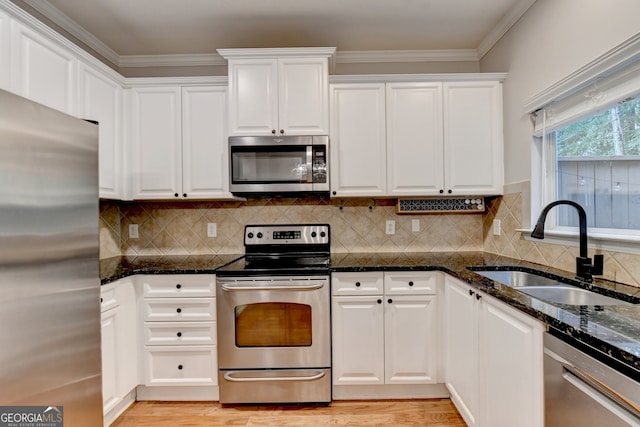 kitchen featuring stainless steel appliances, white cabinets, light wood-type flooring, and sink