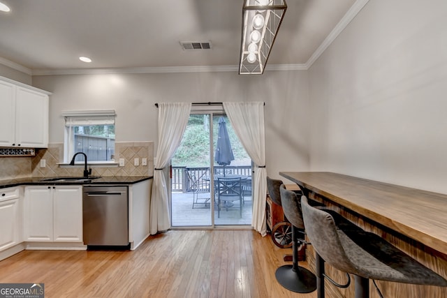 kitchen with white cabinetry, light hardwood / wood-style floors, a healthy amount of sunlight, and stainless steel dishwasher