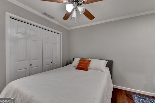 bedroom featuring ornamental molding, hardwood / wood-style floors, ceiling fan, and a closet