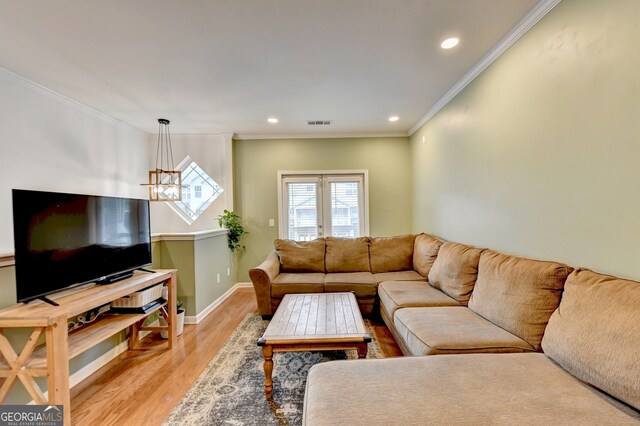 living room with light hardwood / wood-style flooring, french doors, an inviting chandelier, and crown molding