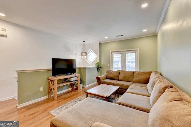 living room featuring a notable chandelier, crown molding, and hardwood / wood-style flooring