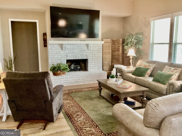 living room with light hardwood / wood-style floors and a brick fireplace