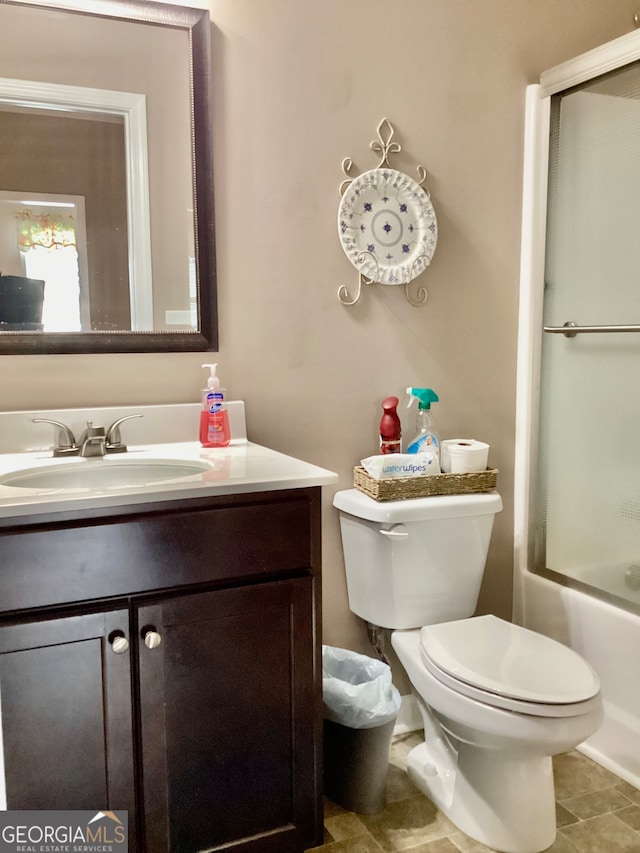 full bathroom with combined bath / shower with glass door, vanity, toilet, and tile patterned flooring