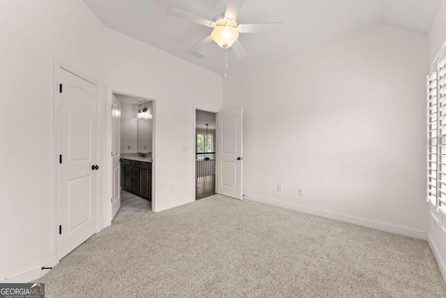 unfurnished bedroom with ensuite bathroom, ceiling fan, light colored carpet, and lofted ceiling