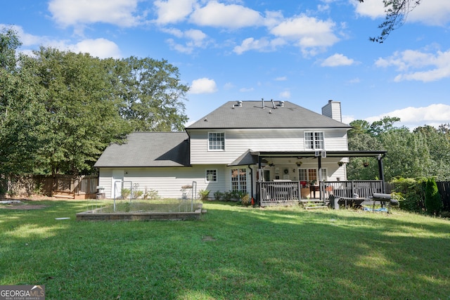 rear view of property with ceiling fan and a yard