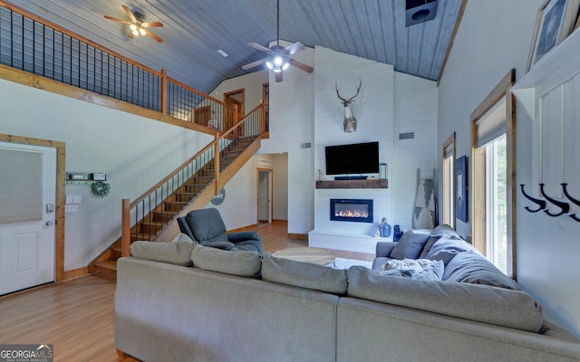 living room featuring a large fireplace, light wood-type flooring, wooden ceiling, and high vaulted ceiling