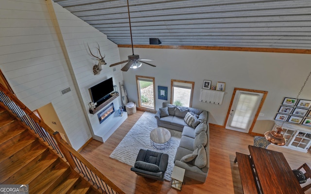 living room featuring ceiling fan, light wood-type flooring, and high vaulted ceiling