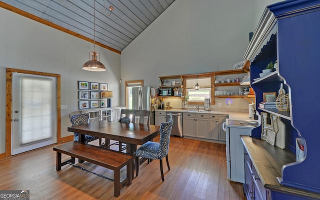 dining space with light wood-type flooring, high vaulted ceiling, and sink