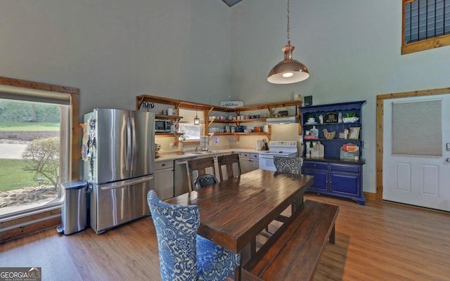 dining room with a high ceiling, light wood-type flooring, and sink