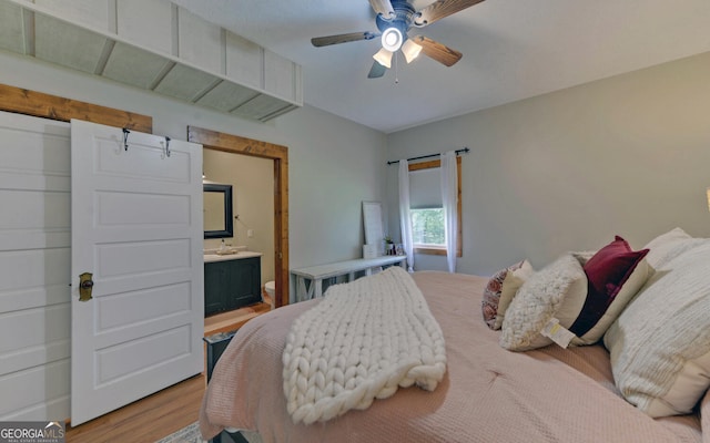 bedroom with ceiling fan, light hardwood / wood-style floors, and ensuite bath