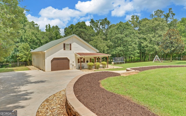 view of front of home with covered porch, a garage, a front yard, and a trampoline